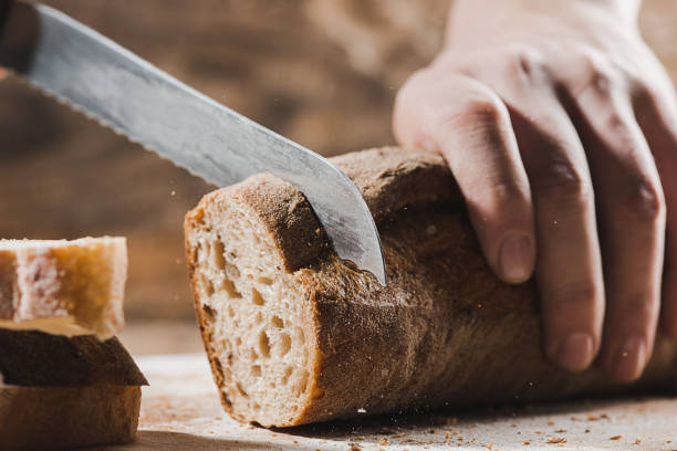 istock Whole grain bread put on kitchen wood plate with a chef holding gold knife for cut 917750714