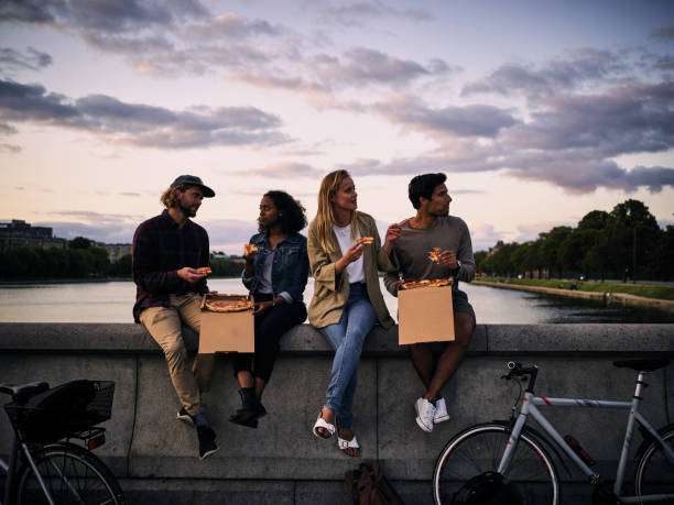 est toujours préférable de manger des pizzas ensemble - candid people casual bicycle photos et images de collection