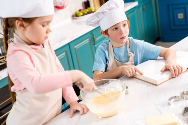 istock cute little kids in chef hats making dough and reading cookbook in kitchen 917753538