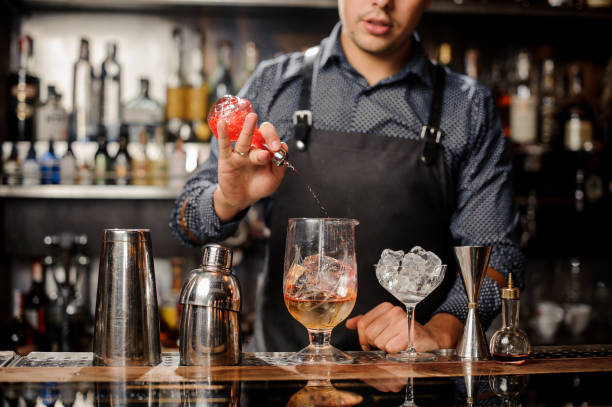 istock Barman pouring red fruit syrup into the large cocktail glass 917755042