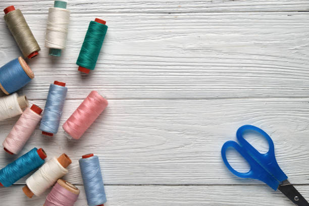 istock Sewing accessories, threads, scissors. Accessories for needlework on a white wooden background. Top view. 917755486