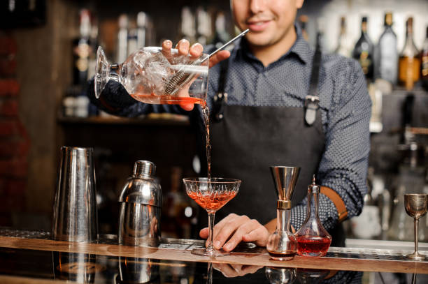 istock Smiling barman adding red alcoholic drink into the cocktail glass 917758528