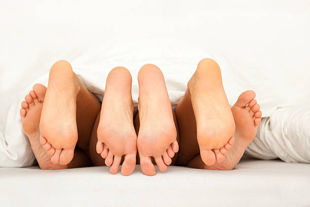 six feet while threesome in bed stock photo