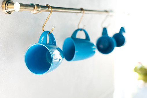 selective focus of empty blue cups hanging in kitchen