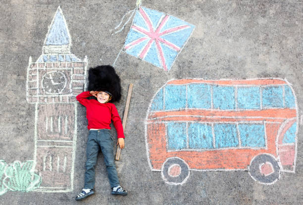 kid boy in british soldier uniform with London chalks picture Happy little kid boy in british queen's guard soldier uniform having fun with London picture drawing with colorful chalks. With Big Ben, Union Jack and red bus as british doodles houses of parliament london photos stock pictures, royalty-free photos & images