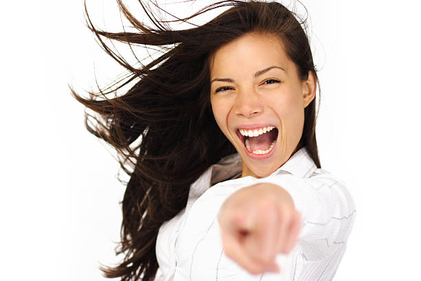 Portrait of excited afro american young woman wearing yellow top and black shorts, holding thought bubble with drawn word yes above her head, pointing with index finger and shouting at camera. Studio shot, white background.
