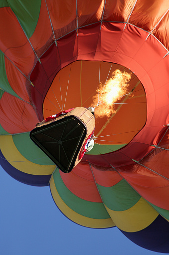 View of the flames fueling a multi-colored, rising hot air balloon - photo shot from directly below.