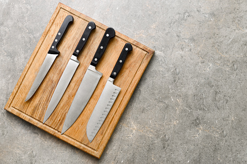 Kitchen knives set laying on wooden cutting board, flat lay, view from above, space for a text