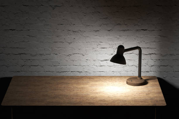 istock Table lamp with yellow light illuminated wooden tabletop 917778516