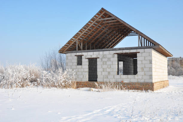 ein haus im winter. neue haus von autoklaviert belüftete betonblöcke vs ziegel mit unfertigen überdachung metall fliesen bau. - home addition attic timber roof beam stock-fotos und bilder