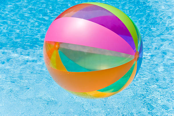 Beach ball floating in a blue swimming pool. Summer background.