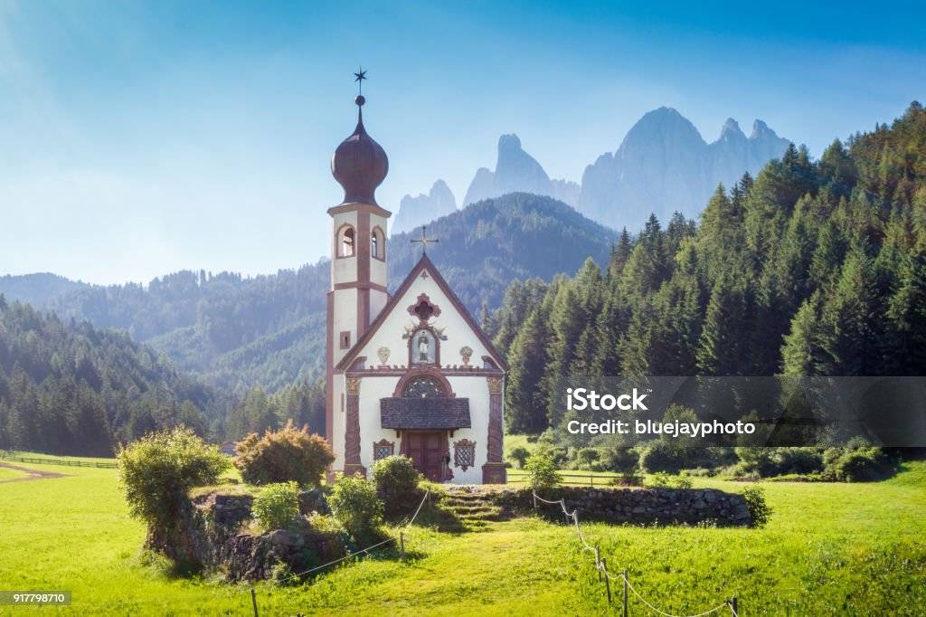 Church of St. Johann of Nepomuk with Odle Group in the Dolomites, South Tyrol, Italy Beautiful view of idyllic mountain scenery with baroque Church of St. Johann of Nepomuk and famous Odle Group in the background on a sunny day with blue sky in the Dolomites in spring, South Tyrol, Italy St. Johann Church - Italy Stock Photo