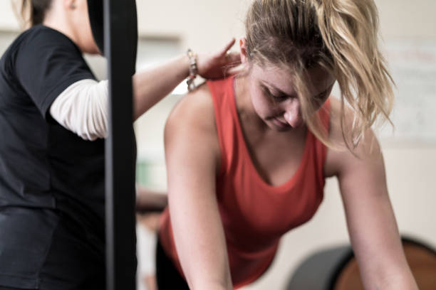 istock Physiotherapist assisting woman while exercising on exercise mat 917799040