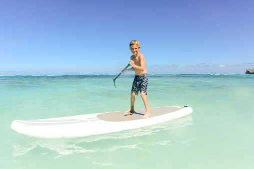 7 Year Old Having Fun On A Paddle Board In Hawaii. Young Boy Having Fun Stand Up Paddling in the Ocean