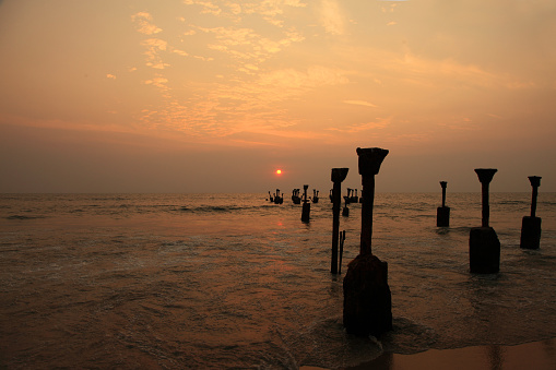 Silhouettes of sea piers during sunset in Calicut beach, Kerala, India