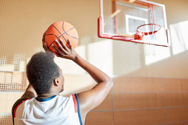 istock Rear view of determined basketball player throwing ball in baske 917812764