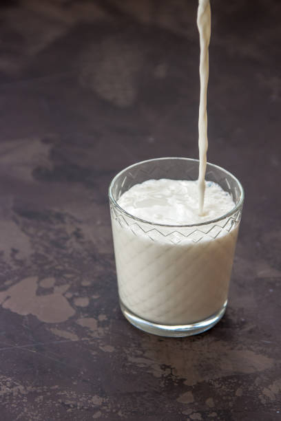 istock Milk pouring into a glass, dark background 917813216