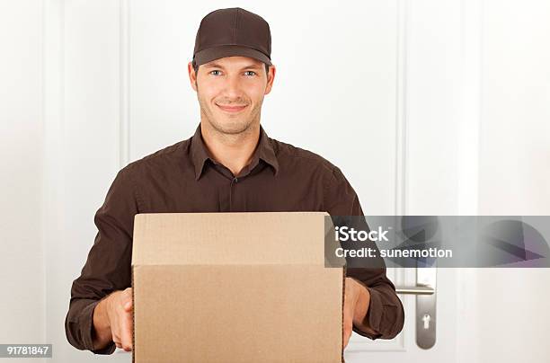 Postman In Formal Brown Clothes With Packet Box Stock Photo - Download Image Now - Box - Container, Delivery Person, Holding