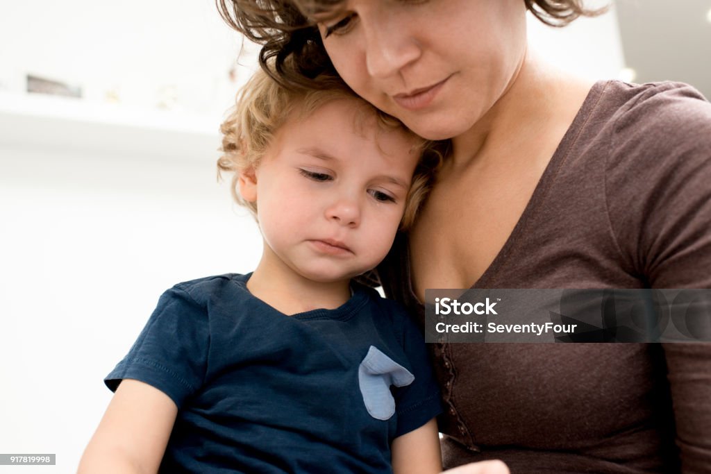Mother Calming Crying Son Close up portrait of cute little boy crying on mothers lap after being hurt Mother Stock Photo