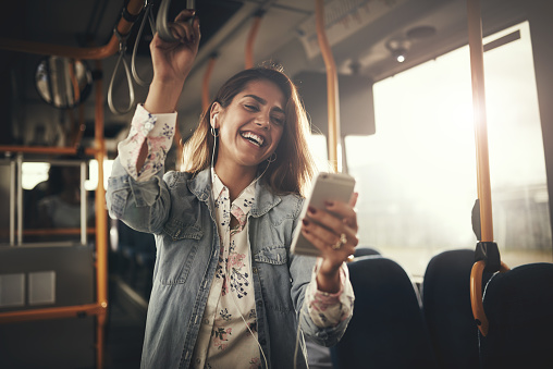 Young woman laughing while listening to music on a bus