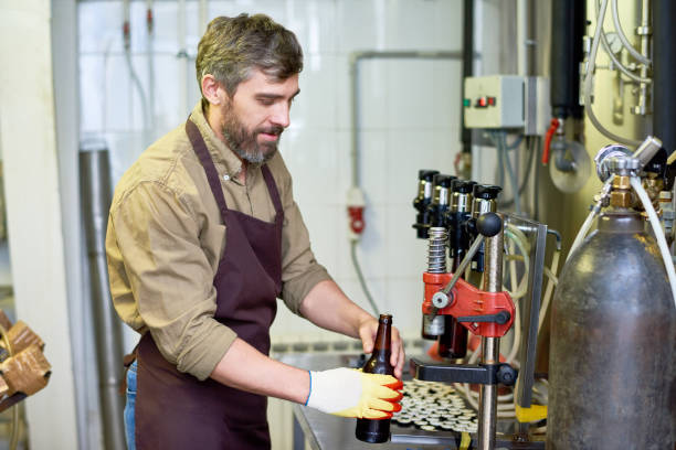 istock Content handsome technician putting beer in bottles at factory 917832606