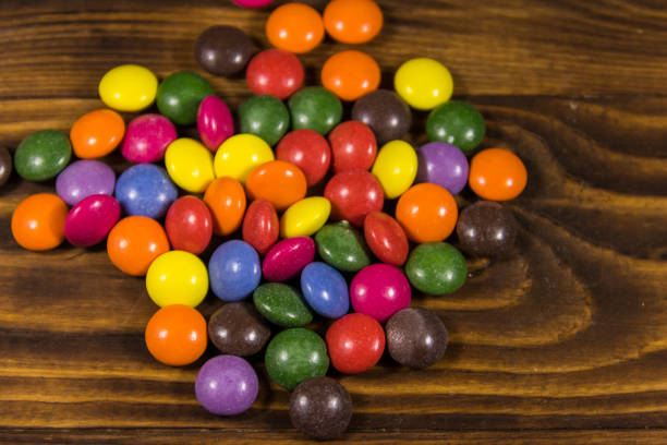 istock Colorful button shaped candies filled with chocolate on wooden table 917837324