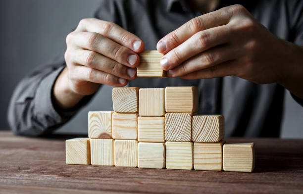 istock Businessman building a pyramid with empty wooden cubes. Concept of business hierarchy and business strategy. 917841124