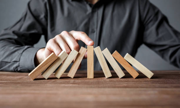 Businessman stopping domino effect with his finger. Security and insurance concept. Businessman stopping domino effect with his finger. Security and insurance concept. curiosity stock pictures, royalty-free photos & images