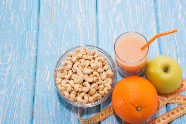 healthy breakfast. The cashew nuts in a white bowl. Green Apple, orange, banana. Flat top view