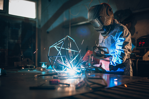 Young artist woman sculpturing using welding machine. Girl power concept