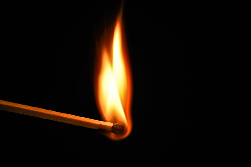 Fire burning on matchstick. Isolated on black background. Macro