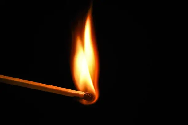 Photo of Fire burning on matchstick. Isolated on black background
