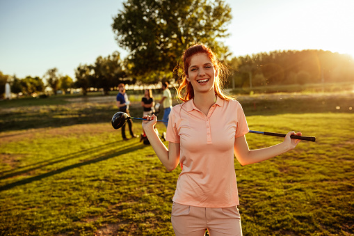 Shot of a happy young woman standing on a golf coarse