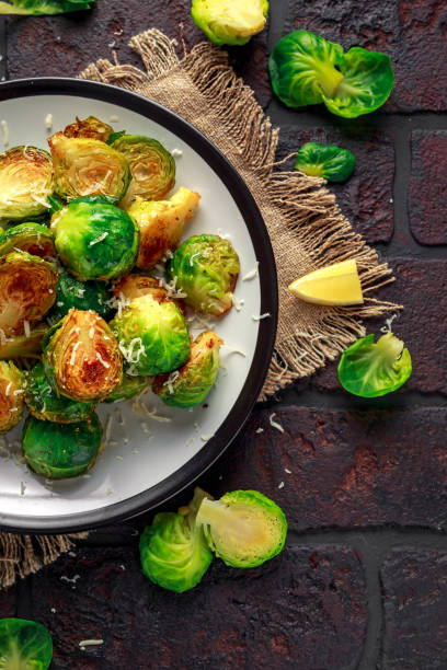 istock Homemade Roasted Brussel Sprouts with Parmesan cheese, lemon, Salt, Pepper on a old stone rustic table 917865450