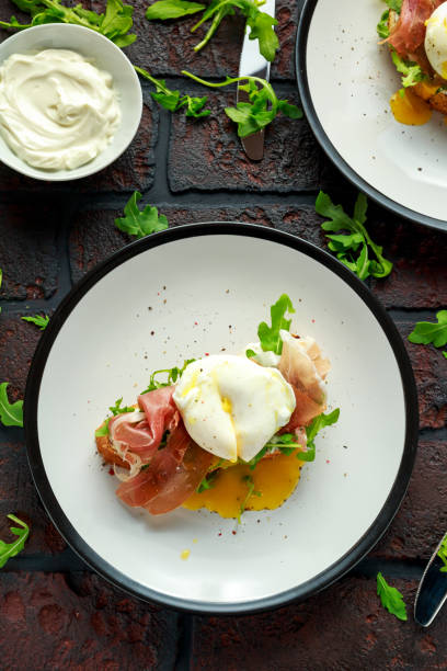 istock Bruschetta with cream cheese, wilde rucola, parma ham and poached egg served on white plate 917865632