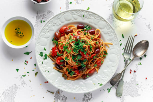 vegetariana italiana pasta alla puttanesca con ajo, aceitunas, alcaparras con placa blanca - aceituna verde fotos fotografías e imágenes de stock