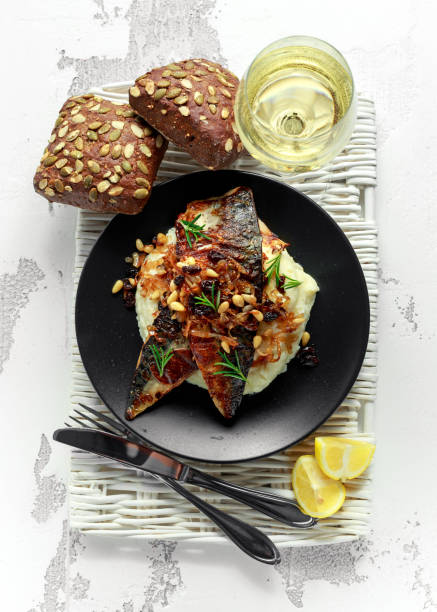 istock Sicilian style mackerel on cauliflower puree with caramelized onions, pine nuts served with rustic bread and white wine 917865786