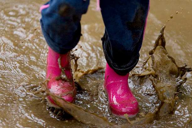 istock Child Wearing Pink Wellington Boots Splashing In A Muddy Puddle 91786614