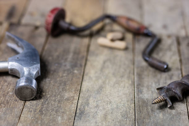 Joinery tools in a workshop. Drill, hammer and other tools on a wooden workshop table. Black background.