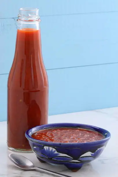 Artisan mexican red hot sauce on retro vintage carrara marble setting, with a spicey hot flavor perfect for all your Mexican, tex-mex recipes and sides.