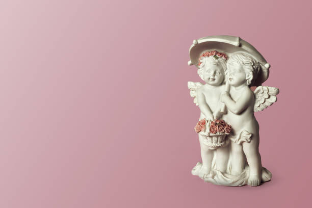 istock Two angels under umbrella on pink background 917874554