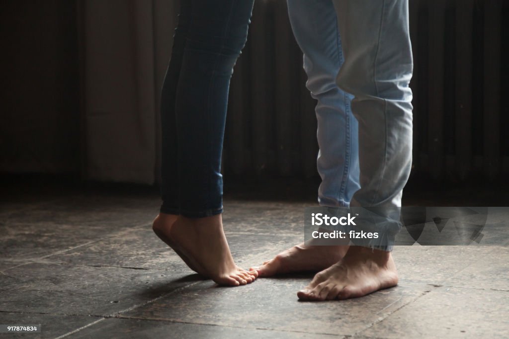Jeune fille debout sur la pointe des pieds pour embrasser l’homme, couple pieds closeup - Photo de Élevé libre de droits