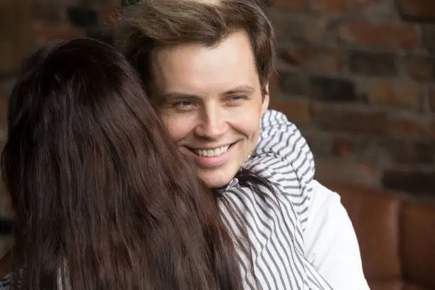 Photo of Young sly liar man happily smiling while woman embracing him