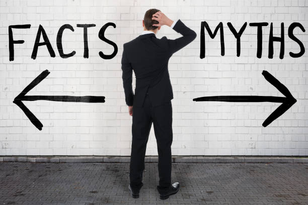 Businessman Looking At Arrow Signs Below Facts And Myths Rear view of confused businessman looking at arrow signs below facts and myths text mythology photos stock pictures, royalty-free photos & images