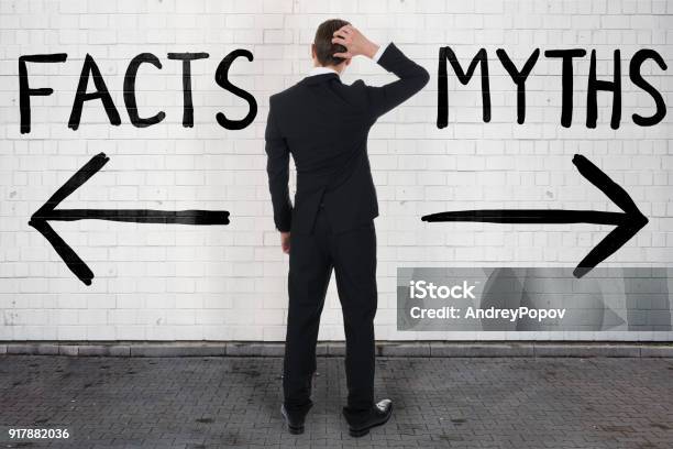 Businessman Looking At Arrow Signs Below Facts And Myths Stock Photo - Download Image Now