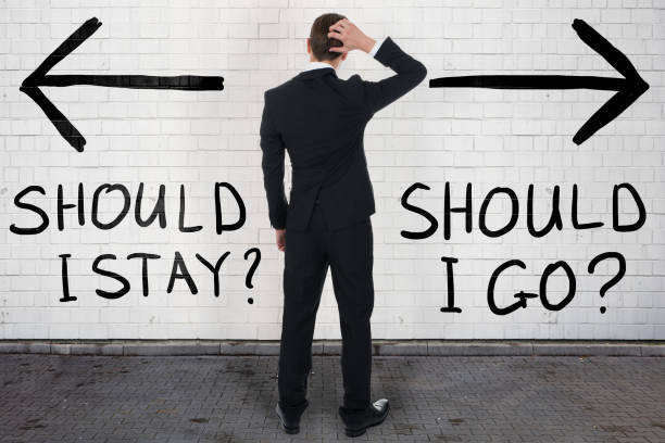 istock Confused Businessman Looking At Should I Stay Or Go Text 917882038