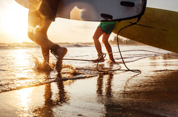 istock Son and father surfers run in ocean waves with long boards 917882140