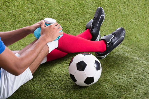 Injured Soccer Player Applying Ice Pack On Knee Close-up Of An Injured Male Soccer Player Applying Ice Pack On Knee physical injury sport ice pain stock pictures, royalty-free photos & images