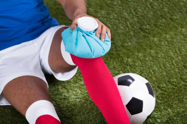 Injured Soccer Player Applying Ice Pack On Knee Close-up Of An Injured Male Soccer Player Applying Ice Pack On Knee physical injury sport ice pain stock pictures, royalty-free photos & images