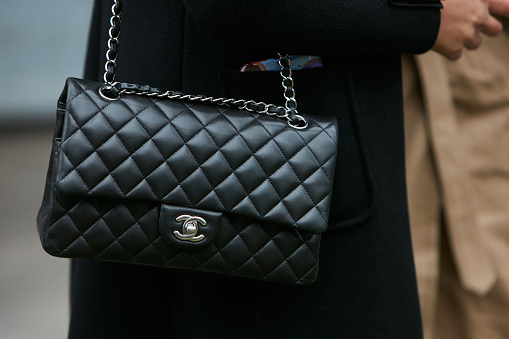 MILAN - JANUARY 15: Woman with black Chanel leather bag with silver chain before Giorgio Armani fashion show, Milan Fashion Week street style on January 15, 2018 in Milan.